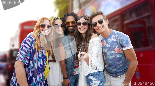 Image of smiling hippie friends with selfie stick in london