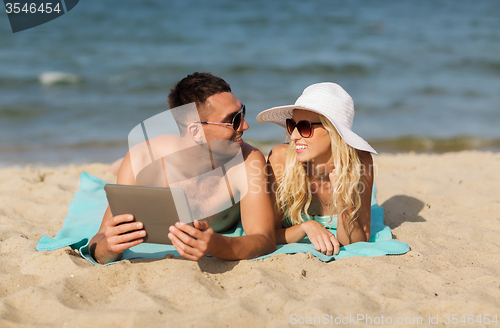 Image of happy couple with tablet pc sunbathing on beach