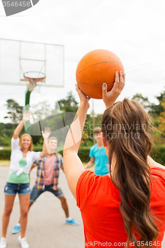 Image of group of happy teenagers playing basketball