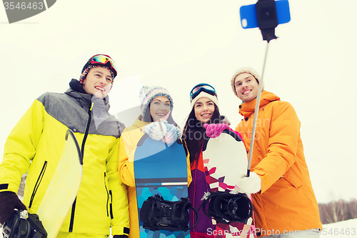 Image of happy friends with snowboards and smartphone