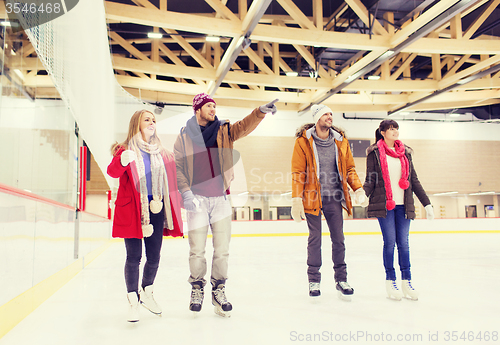 Image of happy friends pointing finger on skating rink