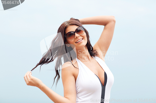 Image of smiling young woman with sunglasses on beach