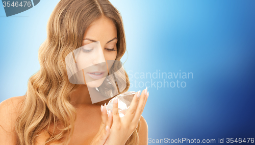 Image of woman holding big diamond over blue background