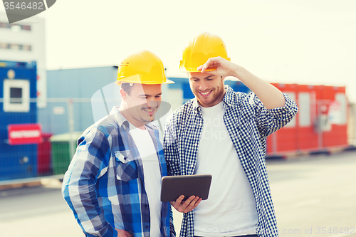 Image of smiling builders in hardhats with tablet pc