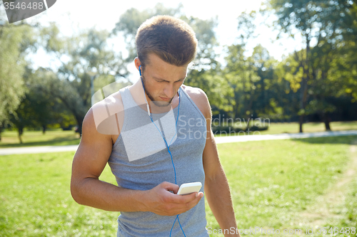 Image of young man with earphones and smartphone at park