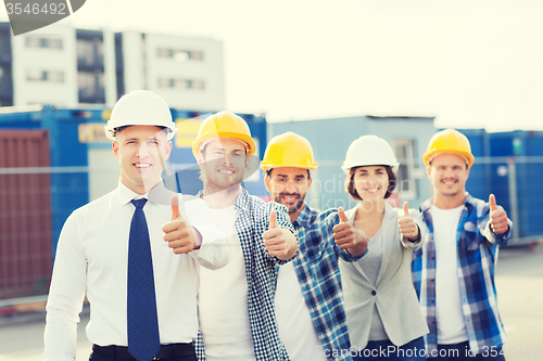 Image of group of smiling builders in hardhats outdoors