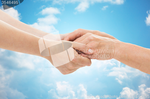 Image of close up of senior and young woman holding hands