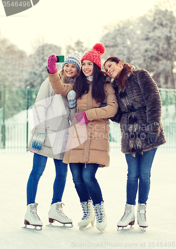 Image of happy young women with smartphone on skating rink