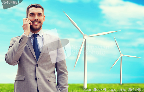 Image of smiling businessman with smartphone outdoors