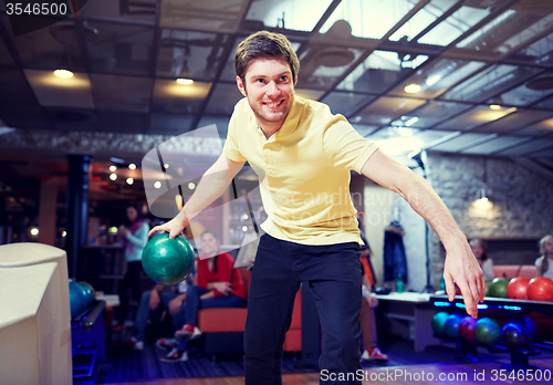 Image of happy young man throwing ball in bowling club