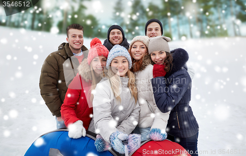 Image of smiling friends with snow tubes and selfie stick