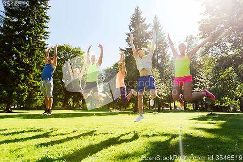Image of group of happy friends jumping high outdoors