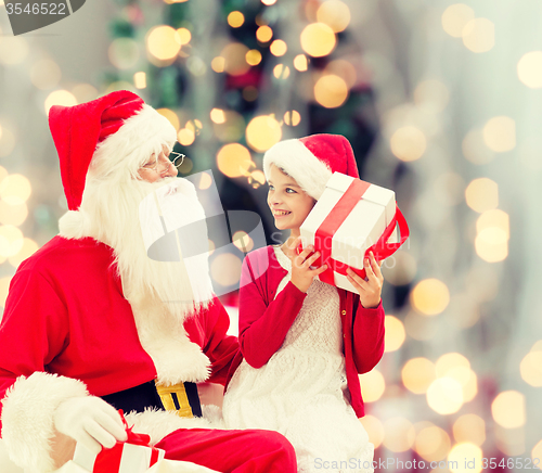 Image of smiling little girl with santa claus and gifts