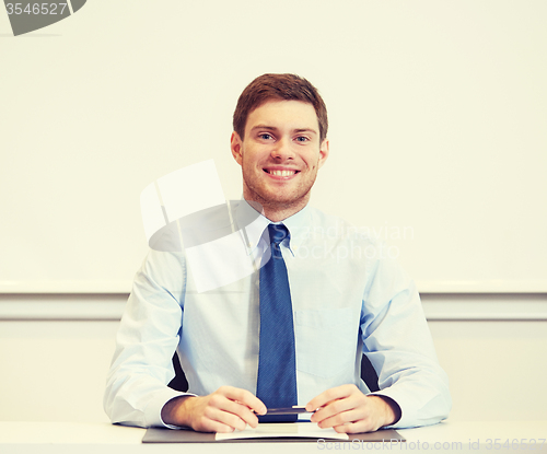 Image of smiling businessman sitting in office