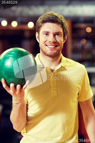 Image of happy young man holding ball in bowling club