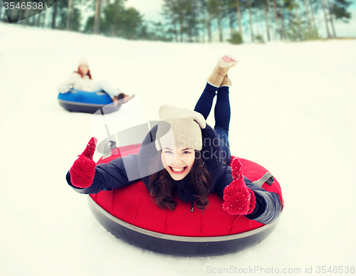 Image of group of happy friends sliding down on snow tubes