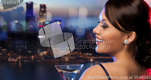 Image of smiling woman holding cocktail over night city