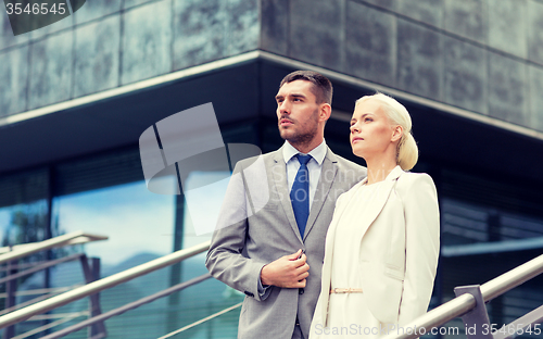 Image of serious businessmen standing over office building