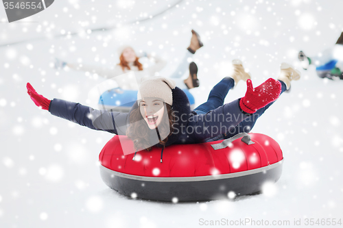 Image of group of happy friends sliding down on snow tubes