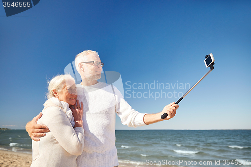 Image of seniors with smartphone taking selfie on beach