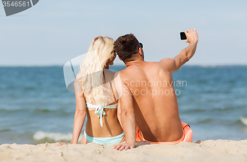 Image of happy couple in swimwear sitting on summer beach