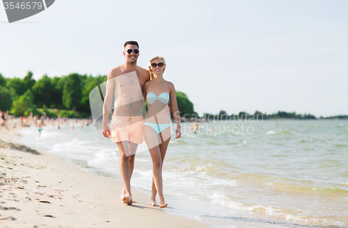 Image of happy couple in swimwear walking on summer beach