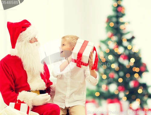 Image of smiling little boy with santa claus and gifts