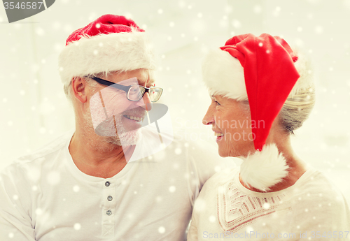 Image of happy senior couple in santa helper hats at home