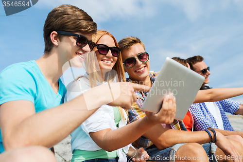 Image of group of smiling friends with tablet pc outdoors