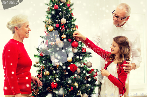 Image of smiling family decorating christmas tree at home