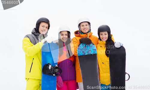 Image of happy friends in helmets with snowboards outdoors