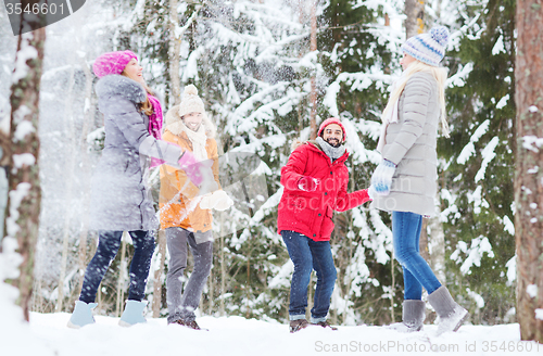 Image of group of happy friends playing snowballs in forest