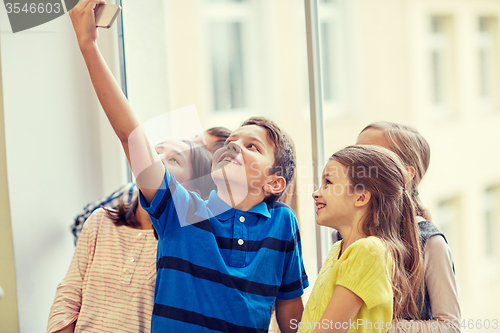 Image of group of school kids taking selfie with smartphone