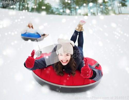 Image of group of happy friends sliding down on snow tubes