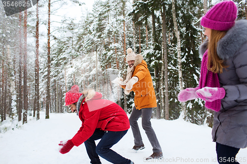 Image of happy friends playing snowball in winter forest