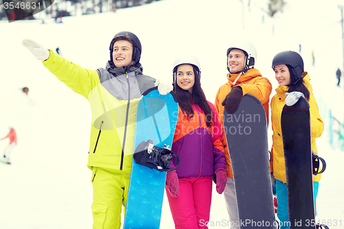 Image of happy friends in helmets with snowboards