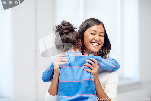 Image of happy mother and daughter hugging at home