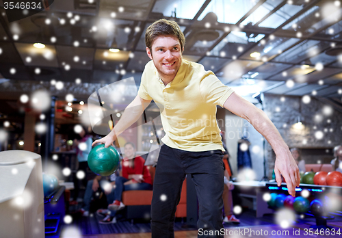 Image of happy young man throwing ball in bowling club