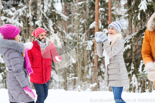 Image of happy friends playing snowball in winter forest