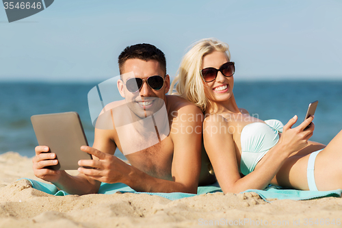 Image of happy couple with tablet pc sunbathing on beach