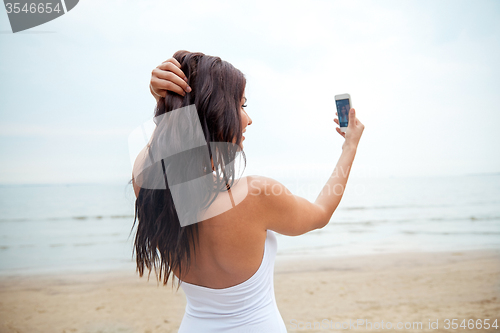 Image of young woman taking selfie with smartphone