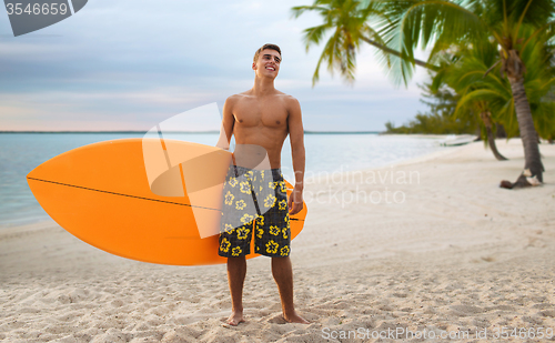 Image of smiling young man with surfboard on summer beach