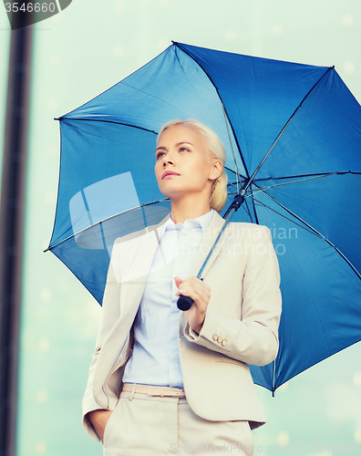 Image of young serious businesswoman with umbrella outdoors