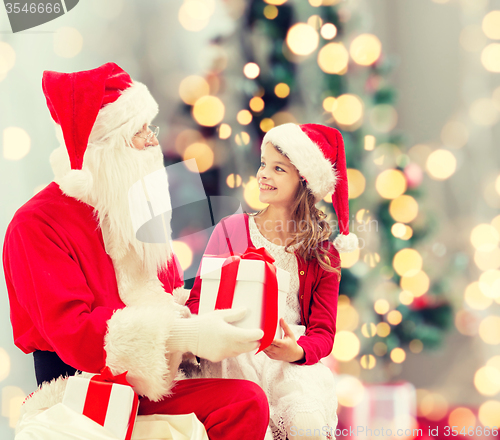 Image of smiling little girl with santa claus and gifts
