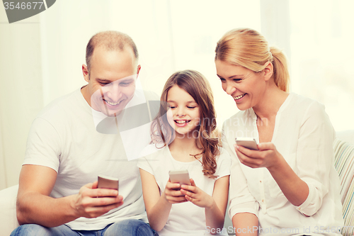 Image of parents and little girl with smartphones at home