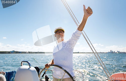 Image of senior man at helm on boat or yacht sailing in sea