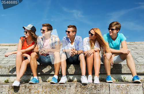 Image of group of smiling friends sitting on city street