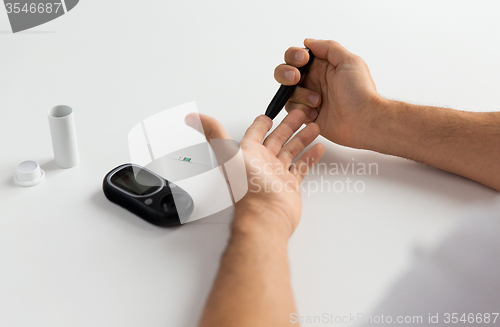 Image of close up of man checking blood sugar by glucometer