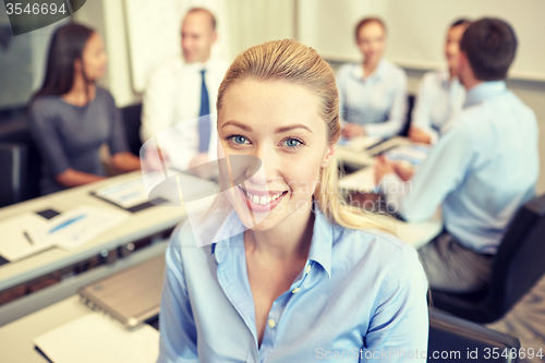 Image of group of smiling businesspeople meeting in office