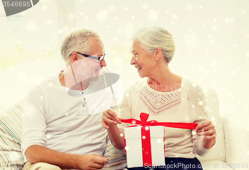Image of happy senior couple with gift box at home